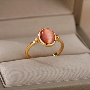 Macro shot of oval cat's eye stone and gold steel ring set in beige jewelry box
