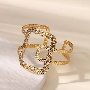 Macro detail of 18K gold plated wide cuff bracelet with hammered texture and geometric cutouts
