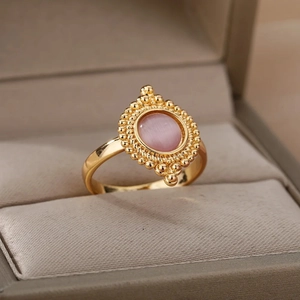 Vintage gold oval ring with pink gemstone and bead detail on a velvet jewelry box display