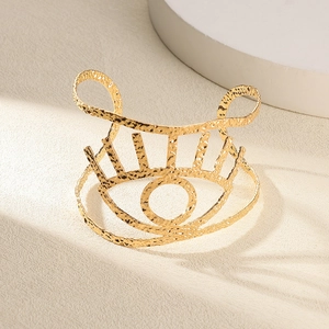 Détail d'un bracelet manchette doré martelé avec motif œil et finition texturée