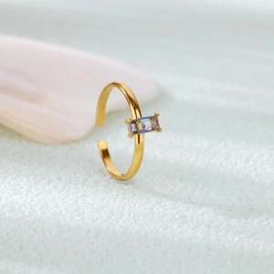 Detail of gold open ring with rectangle blue zircon gemstone on textured backdrop