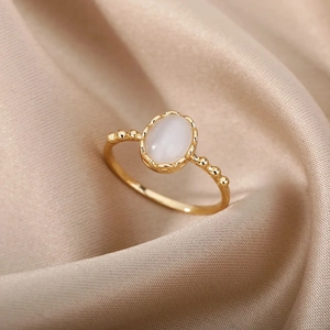 Vue macro d'une bague vintage dorée avec pierre opale ovale sur fond en satin plissé
