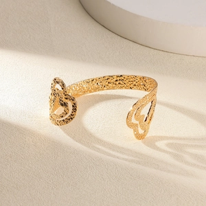 Détail d'un bracelet jonc doré avec découpes en cœur et texture de métal martelé fin