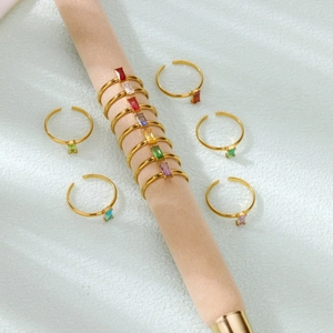 Detail of colorful rectangular zircon birthstone rings on beige textured display stand