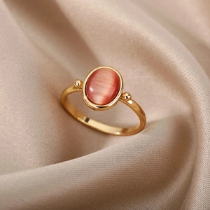 Retro oval pink cat-eye stone ring in gold finish on champagne silk backdrop