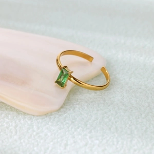 Detailed close-up of emerald green zircon ring with gold band and four-claw setting