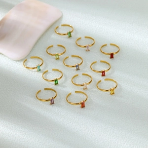 Detail view of colorful birthstone rings with gold bands on light blue background
