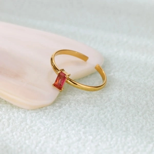 Macro detail of rectangle pink zircon ring with gold band on a decorative shell base