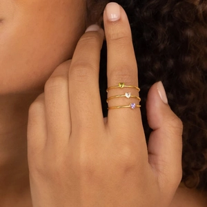 Three-piece set of thin gold rings with heart-shaped zircon birthstones worn by a model