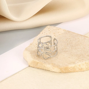 Makro-Detail eines silbernen breiten Rings mit floralen Ausschnitten auf Naturstein