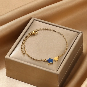 Elegante gouden armband met blauwe ster-hanger op een luxe satijnen sieradendoosje