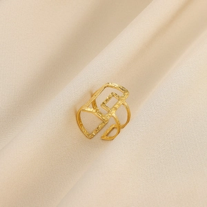 Makroaufnahme von goldenem geometrischem Ring mit strukturierter Oberfläche auf Satin
