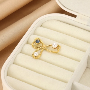 Elegante spilla a fiocco dorato con perle e zaffiro su un cuscino di seta per gioielli