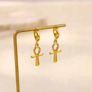 Vergoldete Edelstahl-Ohrringe mit Ankh-Kreuz an einem minimalistischen Schmuckständer hängend