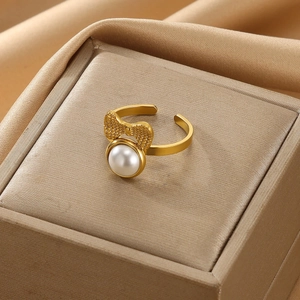 Macro detail of golden bow ring with white faux pearl on silky satin background