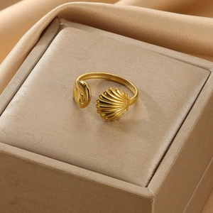 Detailed macro view of adjustable golden shell ring with carved texture on silk background