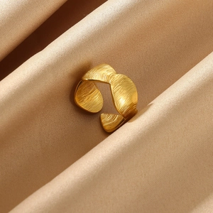 Macro shot of gold textured open ring with brushed metal finish on silk fabric