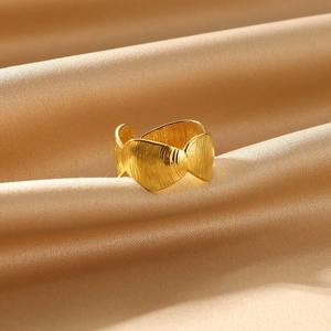 Close-up of golden wide wave ring with brushed texture on elegant silk background