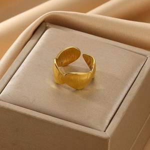 Detailed view of an adjustable gold pearl ring with a brushed texture on satin fabric