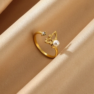 Detail of gold butterfly ring with pearl and zircon inlay on champagne satin background