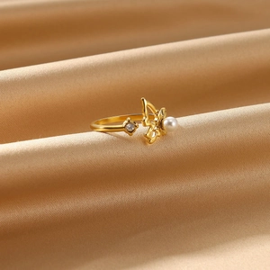 Detail shot of golden butterfly ring with white pearl and zircon on satin fabric