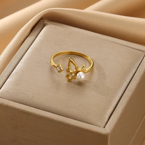 Detail of gold open ring featuring a cutout butterfly, white pearl and starburst stone