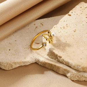 Detailed close-up of a golden butterfly ring with a white pearl and sparkling zircon stone