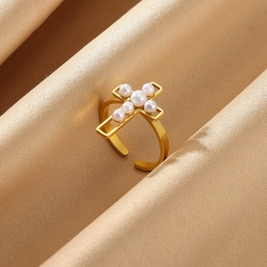 Detailed close-up of a gold cross ring with pearls on a luxury satin background