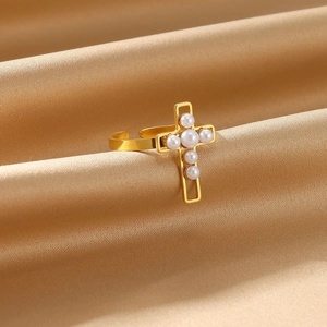 Detailed close-up of a gold cross ring with white pearls on a silk background