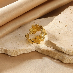 Detail of vintage golden flower open ring featuring three 3D daisy designs on a stone surface