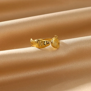 Detailed close-up of golden kissing fish open ring on elegant champagne satin fabric