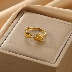 Macro detail of golden open ring featuring artistic whale and fish design on silk