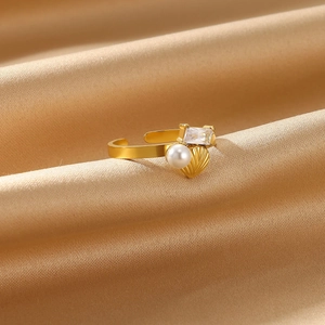 Detailed close-up of golden ring with white pearl and rectangular gem on silk background