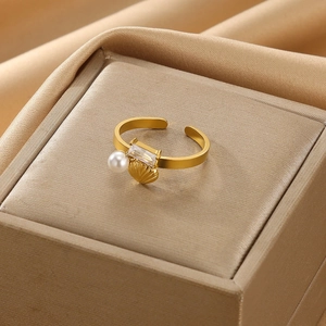 Detail shot of a gold stainless steel open ring with faux pearl, zircon and shell charm