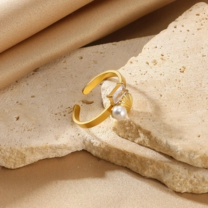 Detail of adjustable gold ring featuring white pearl and rectangular zircon stone