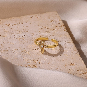 Elegant gold-tone cross ring with shimmering crystals on a chic stone pedestal