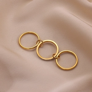 Three-piece stackable gold stainless steel ring set with zircon accents on satin fabric