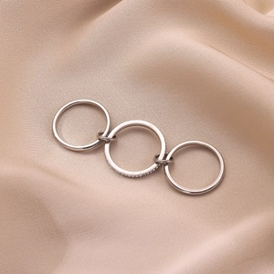 Macro detail of triple-layer stainless steel ring with zircon stones on beige silk cloth