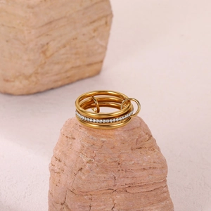 Three-layer gold stacked ring with micro-pave crystals on natural stone background