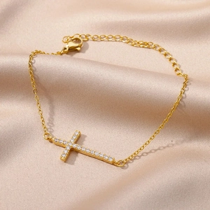 Bracciale a croce in rame placcato oro 18k con zirconi su elegante sfondo di seta