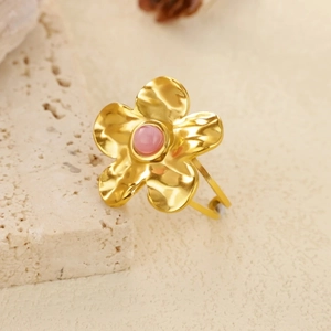 Detail of gold flower ring featuring a pink cabochon gemstone and hammered petals on stone