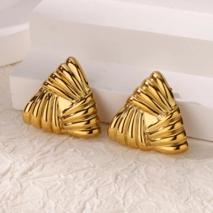 Detail of gold-plated geometric triangle earrings with sunburst fan texture on white steps