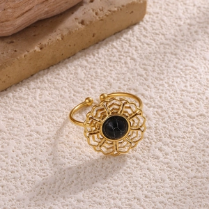 Close-up of gold plated bow ring featuring hollow floral design and marble stone