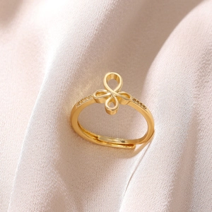 Detail of 18K gold plated bow ring with sparkling zircons on elegant champagne silk fabric