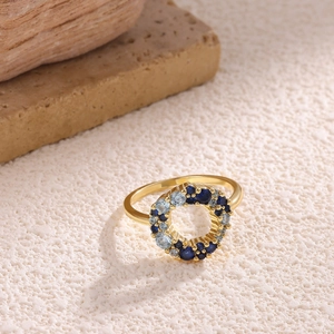 Detail of 18K gold ring featuring a halo of dark and light blue sapphire-like gemstones
