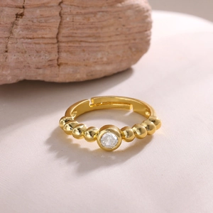Close-up of 18K gold plated bow ring with beaded band and sparkling zircon center stone