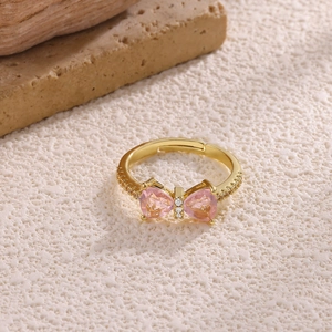 Detailed macro shot of bow-shaped ring with pink heart zircons and 18K gold finish