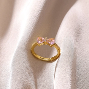 Detailed view of adjustable gold bow ring featuring pink heart zircon and fine grain texture