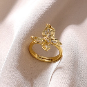 Detailed macro shot of a gold butterfly ring with shimmering white zircon wings on silk