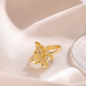 Close-up of golden bow-knot butterfly ring with shimmering zircon on silk background